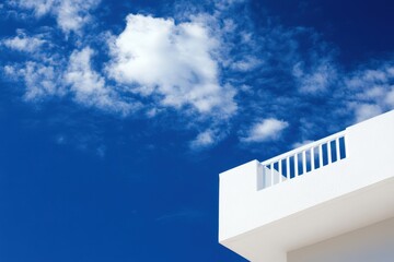 A white building with a balcony and a blue sky in the background