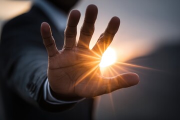 A hand is raised in the air, with the sun shining on it