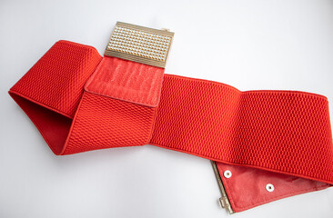Red fashionable women's knitted elastic band belt with metal buckle with rhinestones, isolated on white background
