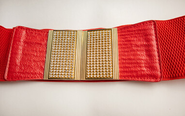 Red fashionable women's knitted elastic band belt with metal buckle with rhinestones, isolated on white background