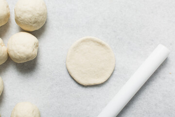 Overhead view of steamed bun dough being shaped on a white granite countertop, process of making steamed buns