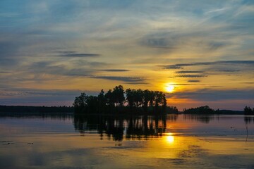 Obraz premium Sunset over a tranquil lake with an island silhouette