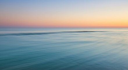 Serene ocean view at sunrise with calm water reflecting the vibrant sky colors.