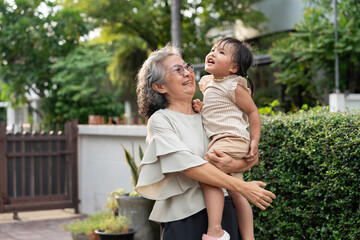 A cheerful grandmother embraces her granddaughter in the home, sharing a special moment. Their bond...