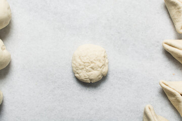 Overhead view of steamed bun dough being shaped on a white granite countertop, process of making...