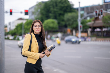 Fototapeta premium A woman wearing glasses and a yellow jacket is holding a book