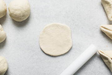 Overhead view of steamed bun dough being shaped on a white granite countertop, process of making steamed buns