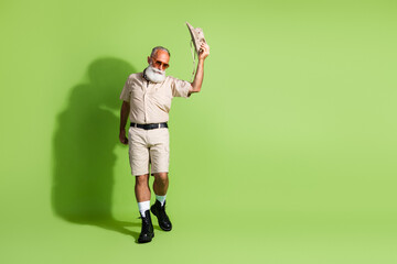 Elderly bearded man in safari outfit exploring on green background, enjoying a summer expedition...