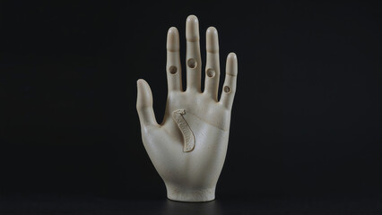 Mannequin hand showing palm with stigmata and holes on black background