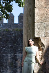 A beautiful Latin teenager with long dark hair poses on the stones of an abandoned castle on the...