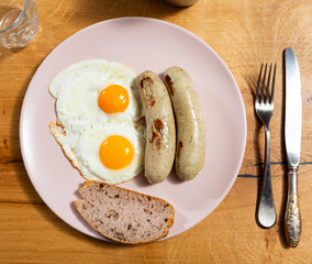 Delicious fried eggs with sausage served on platter for breakfast