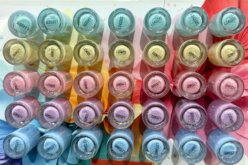 A colorful arrangement of nail polish bottles in various pastel shades. The bottles are neatly organized in rows, showcasing a vibrant spectrum of colors.