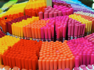Colorful arrangement of markers in various shades, including pink, orange, and yellow. The scene showcases vibrant stationery items in a retail display.