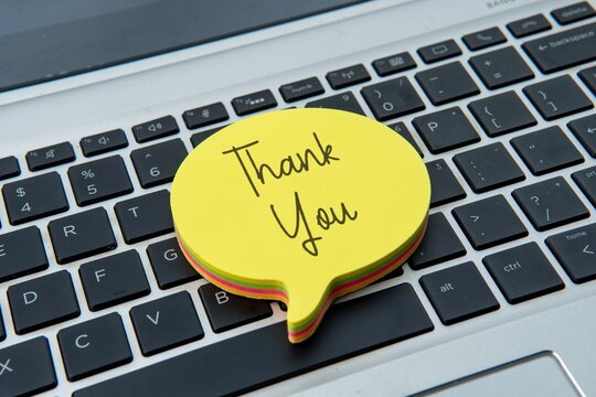 A sticky note with "Thank You" on top of a laptop keyboard. Gratitude, appreciation, recognition, and positive interaction in a modern workspace.
