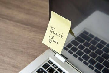 A sticky note with "Thank You" on the corner of a laptop. Gratitude, appreciation, recognition, and positive interaction in a modern workspace.