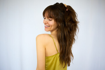 Obraz premium Beautiful happy playful brunette with the big smile holding her beautiful long thick hair on the white background