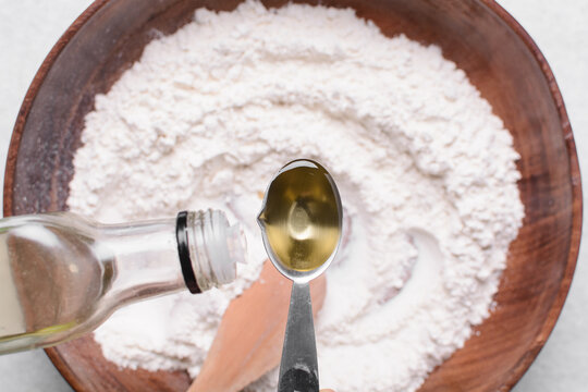 top view of olive oil in a measuring spoon, overhead view of measuring a tablespoon of oil