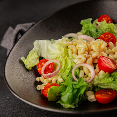 Pasta salad green leaf lettuce, tomato, pasta, onion fresh delicious gourmet food background on the table rustic food top view copy space keto and paleo diet vegan and vegetarian food