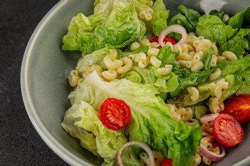 Pasta salad green leaf lettuce, tomato, pasta, onion fresh delicious gourmet food background on the table rustic food top view copy space keto and paleo diet vegan and vegetarian food