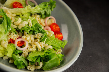 Pasta salad green leaf lettuce, tomato, pasta, onion fresh delicious gourmet food background on the table rustic food top view copy space keto and paleo diet vegan and vegetarian food
