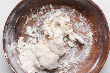 Overhead view of paratha dough being mixed in a wooden bowl, top view of flaky flatbread dough in a wood bowl, process of making paratha