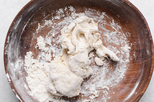 Overhead view of paratha dough being mixed in a wooden bowl, top view of flaky flatbread dough in a wood bowl, process of making paratha