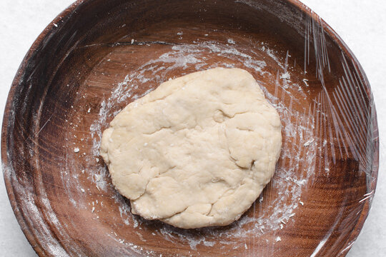 Overhead view of paratha dough being mixed in a wooden bowl, top view of flaky flatbread dough in a wood bowl, process of making paratha