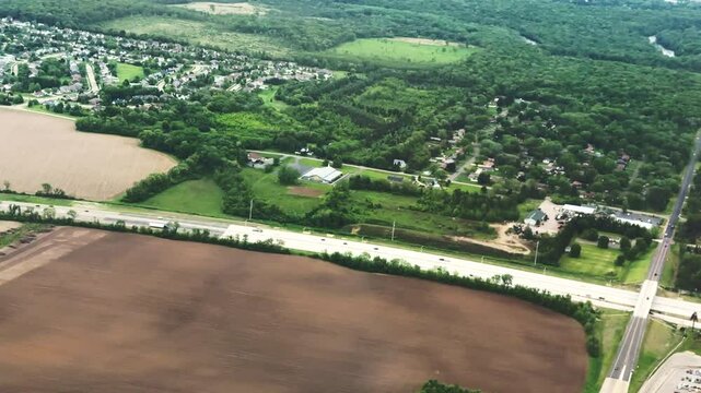 In-flight passenger view of highway, woods, neighborhoods, streets, and other landmarks on low-altitude approach to Chicago Rockford International Airport in northern Illinois, morning in mid May