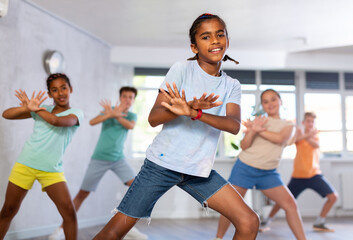 African man child dances waacking in choreographic school, group of young people in sportswear...