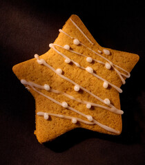 Weihnachtsgebaeck Muerbeteig Stern auf schwarzem Fond mit Zuckerguss, Keks, Sternkeks,