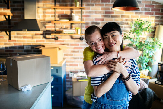 Lesbian couple sharing a tender moment while unpacking boxes in their new kitchen