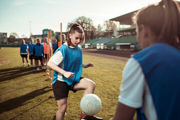 Teenage girl practicing soccer skills during training session on a football field