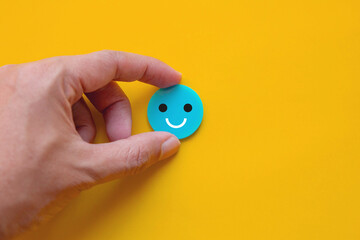 Concept of mental health and positive thinking; Hand holding smiley face