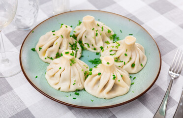 Appetizing traditional Georgian meat khinkali served with greens on plate