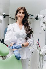 Portrait of a young female dentist in uniform at a modern dental clinic, smiling confidently.