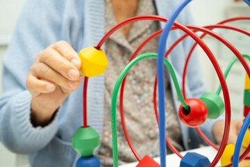 Asian elderly woman playing enhancing skill board game.