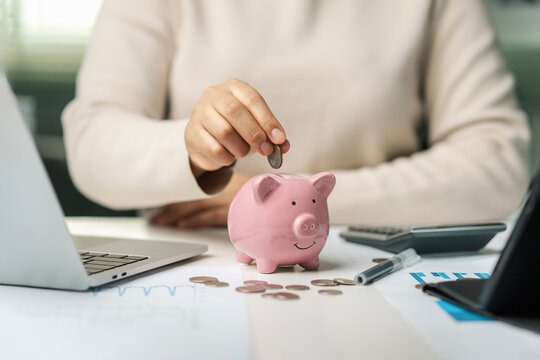 Female hand holding a pink piggy bank with coins in it. Investment concept of saving money. Saving money, planning and accounting.