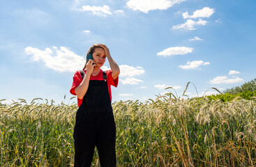 Agricultural crisis and decline. Worried female farmer listening to phone call with hand on...
