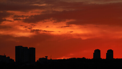 Silhouette of constructing buildings against amazing sunset red sky.