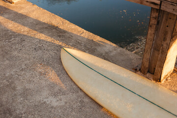 Beige surfboard in the sun. Surfer shortboard on a concrete background in the rays of the setting sun. The concept of sport and surfing on the islands