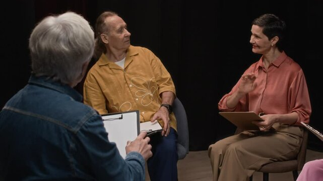 Rear view of grey-haired male teacher working with mature Caucasian couple rehearsing script during drama class