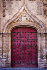 Reggio Emilia, Italy, 01.04.2025. Ancient arched stone entrance with decorative carvings and vintage red door with iron details