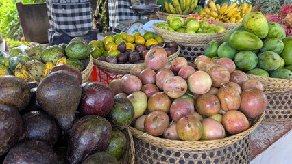 Beautiful Balinese market stall display of fresh fruit and vegetables including avocado, mangoes, passionfruit, and bananas on tropical island of Bali, Indonesia