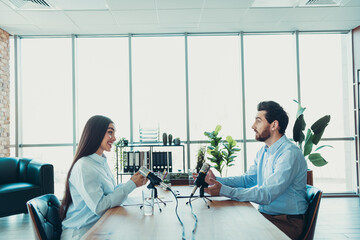 Two professionals recording a podcast in a modern workspace, symbolizing collaboration, creativity,...