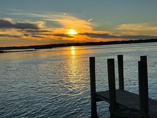 Wooden dock at golden sunset over quiet bay