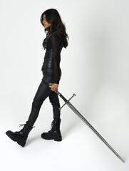 Fantasy female warrior in leather armour  full body studio portrait of fierce brunette in catsuit...