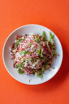 Carpaccio met rucola en Parmezaan op witte schaal