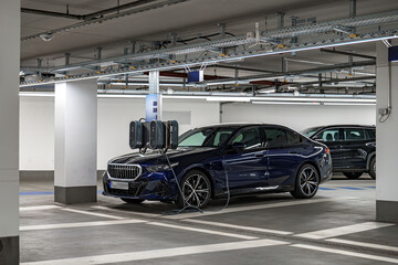 Electric car charging in underground parking lot during late evening hours with modern lighting