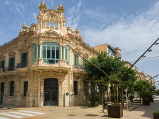 Casa Brunet, an art nouveau building with turquoise windows in Tortosa, Spain, under a clear blue sky. Shot taken from public street.