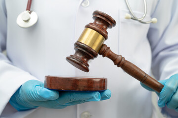 Asian doctor holding court hammer for and crime law justice, forensic medicine.